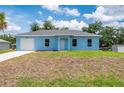 Single-story blue home with a well-maintained lawn and attached garage at 21480 Eldred Ave, Port Charlotte, FL 33952