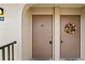 Close-up of tan unit entrance doors, one decorated with a colorful floral wreath at 25100 Sandhill Blvd # R201, Punta Gorda, FL 33983