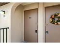 Close-up of tan unit entrance doors, one decorated with a colorful floral wreath at 25100 Sandhill Blvd # R201, Punta Gorda, FL 33983