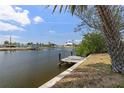 Waterfront backyard view with a weathered wooden dock, lush greenery, and tranquil canal waters at 453 Carolyn Ln, Punta Gorda, FL 33950