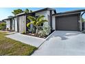 Inviting home entrance featuring fresh landscaping, a modern color scheme, and an attached one-car garage at 5520 Kenwood Dr, North Port, FL 34287