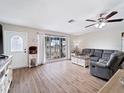 Cozy living room with wood-look floors, a ceiling fan, and a large window providing ample natural light at 6531 Marius Rd, North Port, FL 34287