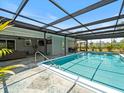 Inviting in-ground pool with a screened enclosure and stone patio, perfect for outdoor relaxation and entertainment at 6531 Marius Rd, North Port, FL 34287