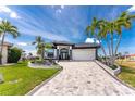 Beautiful home with well-manicured landscaping, brick driveway, and tropical palm trees at 1255 Eider Ct, Punta Gorda, FL 33950