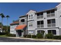 Condo building with screened balconies, red tile roof, gray facade, and parking in the foreground at 18001 Richmond Place Dr # 636, Tampa, FL 33647