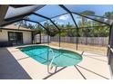 Enclosed inground pool with screened enclosure and an adjacent white tool shed at 21080 Firwood Ter, Port Charlotte, FL 33954