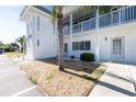 Close-up of a pristine white condo exterior featuring a well-kept lawn and a small palm tree at 22375 Edgewater Dr # 128, Port Charlotte, FL 33980