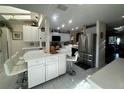 Bright kitchen with breakfast bar, white cabinets, stainless refrigerator, and tile floors at 25188 Marion Ave # 1004, Punta Gorda, FL 33950