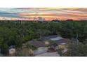 Aerial view of a beautiful home with a screened pool, surrounded by lush green landscape under a gorgeous sunset at 3400 Allapatchee Dr, Punta Gorda, FL 33950