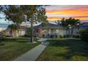 Charming single-story home boasts a manicured lawn, walkway, mature trees, and covered porch seating during sunset at 526 Allen St, Punta Gorda, FL 33950
