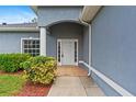 Close-up of the front entrance featuring a white door, brick landing, and manicured landscaping at 1275 Huntington St, North Port, FL 34288