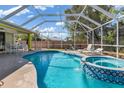 Sparkling screened-in pool and hot tub featuring a serene waterfall feature and plenty of space for outdoor lounging and entertaining at 1313 Wise Dr, North Port, FL 34286