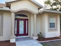 Inviting front entrance with elegant columns, a security camera, and tasteful landscaping at 1488 Squaw Ln, North Port, FL 34286