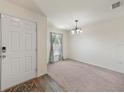 Inviting living room features plush carpet, a front door, and a decorative light fixture at 23470 Burlingame Ave, Punta Gorda, FL 33980