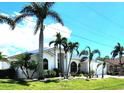 Beautifully landscaped front of the home with lush lawn, palm trees and large picture windows at 3520 Caya Largo Ct, Punta Gorda, FL 33950