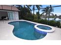 Inviting in-ground pool featuring a connected hot tub, and a screened enclosure with an expansive view at 3787 Whippoorwill Ct, Punta Gorda, FL 33950