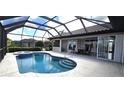 Backyard pool featuring a screened-in enclosure, outdoor kitchen, patio dining area, and lush landscaping at 3787 Whippoorwill Ct, Punta Gorda, FL 33950