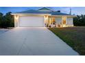 Well-lit single-Gathering home with a two-car garage, bright entryway, and a neatly paved driveway at dusk at 7122 Turner St, Englewood, FL 34224