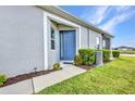 Inviting home entrance featuring a blue front door, tidy landscaping, and a modern exterior finish at 1678 Royal Ct, Punta Gorda, FL 33980