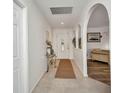 Bright foyer with neutral tile flooring, an arched doorway, and glass table with decor at 20355 Mount Prospect Ave, Port Charlotte, FL 33952
