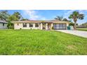 Charming single-story home featuring a well-kept lawn, neutral colors and a paved driveway leading to a garage at 20355 Mount Prospect Ave, Port Charlotte, FL 33952