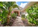 Inviting front entrance with lush landscaping, a brick walkway, and a charming covered porch at 2087 Lynx Run, North Port, FL 34288