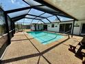 Relaxing screened-in pool area with clear blue water, patio furniture, and plenty of space for lounging at 261 Caddy Rd, Rotonda West, FL 33947