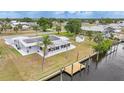 Rear exterior showcasing new solar panels, screened patio, and wooden dock on the canal at 27385 Voyageur Dr, Punta Gorda, FL 33983