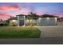 Charming home features a spacious two-car garage and a well-manicured lawn at dusk at 3544 Monfero Ave, North Port, FL 34286