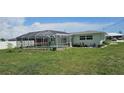 View of backyard with a screened-in pool, surrounding landscaping, and the home's exterior at 570 Mimosa Nw Ave, Port Charlotte, FL 33952
