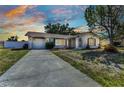 Beautiful sunset view of a single-story home with lush front yard, attached garage, and welcoming front entrance at 6753 Thorman Rd, Port Charlotte, FL 33981