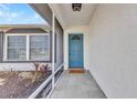 Inviting covered front porch with a blue door, stylish gray tile flooring, and decorative plants at 6753 Thorman Rd, Port Charlotte, FL 33981