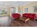 Bright living room featuring hardwood floors, natural light, and comfortable red sofa set at 857 Macaw Cir, Venice, FL 34285