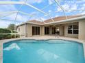 Relaxing screened-in pool area with large patio and beautiful blue tile and tranquil water at 857 Macaw Cir, Venice, FL 34285