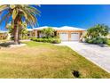 Beautifully landscaped single-story home featuring a pristine driveway and tropical accents at 1374 Grebe Dr, Punta Gorda, FL 33950