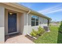Home's exterior boasts a blue front door, a well-kept lawn, and coordinated landscaping at 16079 Bandermill Dr, Port Charlotte, FL 33953