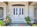 Elegant front door with glass panels and a quaint porch setting, complemented by lush greenery and decorative accents at 17210 Chase Ave, Port Charlotte, FL 33948