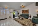 The cozy living room is complete with tile flooring, a ceiling fan, and comfortable seating around a decorative rug at 17210 Chase Ave, Port Charlotte, FL 33948