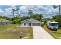 Inviting single-story home with a gray exterior, landscaped front yard and a two-car garage at 21310 Quesada Ave, Port Charlotte, FL 33952