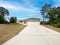 Well maintained single-story home with a large driveway and front yard, surrounded by mature trees at 2336 Redfern St, Port Charlotte, FL 33948