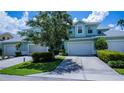 Charming blue two-story townhome featuring a two-car garage, well-maintained lawn, and lush landscaping at 25511 Heritage Lake Blvd # 8, Punta Gorda, FL 33983