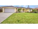 Charming one-story home with a lush green lawn, two-car garage and manicured landscaping at 474 Lomond Dr, Port Charlotte, FL 33953