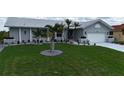 Charming one-story home featuring a well-manicured lawn, mature palm trees and a one-car garage at 745 Monaco Dr, Punta Gorda, FL 33950