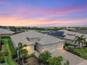 Charming home featuring a three-car garage, paver driveway, and beautiful landscaping under a colorful sky at 17556 Winding Wood Ln, Punta Gorda, FL 33982