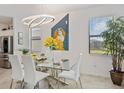 Bright dining room with a glass table, white chairs, modern lighting, and stylish décor at 1993 E Isles Rd, Port Charlotte, FL 33953