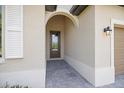 Covered front entry features a tiled floor, a dark wood door with glass, and an exterior light fixture at 1993 E Isles Rd, Port Charlotte, FL 33953