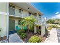Charming condo exterior with lush landscaping, a small palm tree, and a cozy seating area at 25225 Rampart Blvd # 1603, Punta Gorda, FL 33983