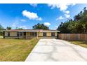Charming ranch home with a front porch, green trim, long cracked driveway, and a well-maintained lawn at 30154 Beech Rd, Punta Gorda, FL 33982