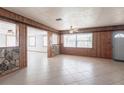 Spacious living room with tile flooring, stone accents, wood paneling, ceiling fan, and natural light at 30154 Beech Rd, Punta Gorda, FL 33982
