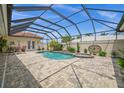 Screened-in pool area with a heated pool, spa, lush landscaping, and outdoor seating at 3050 Rivershore Ln, Port Charlotte, FL 33953